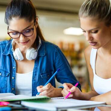 Group of happy young female studying together in college library. Study education people concept