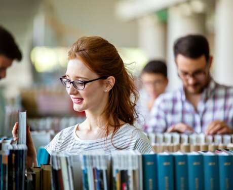 Happy university students studying with books in library. Group of multiracial people in college