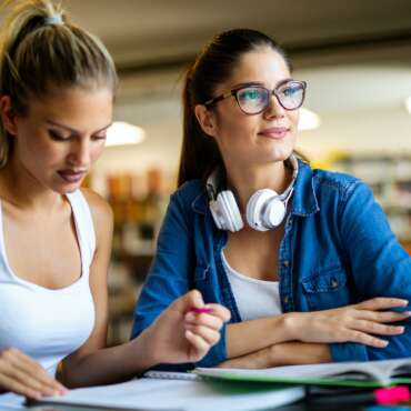 Portrait of happy young people studying together in a library. Education study teenager concept